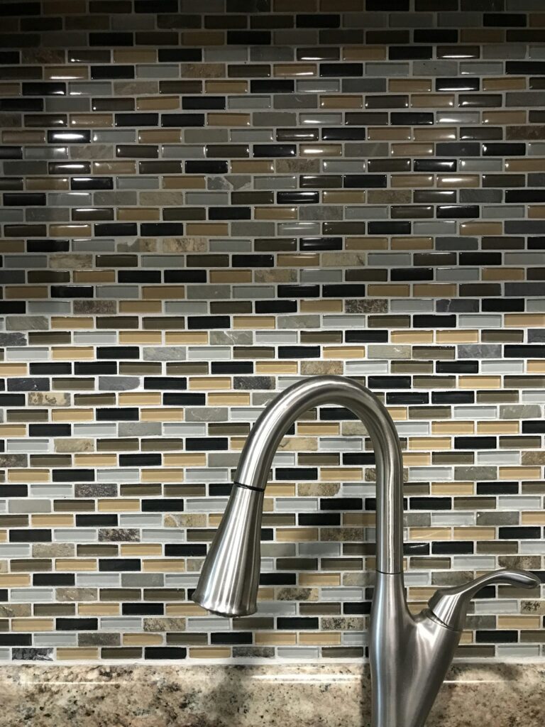 Small mosaic reflective tile backsplash behind kitchen faucet In house or home